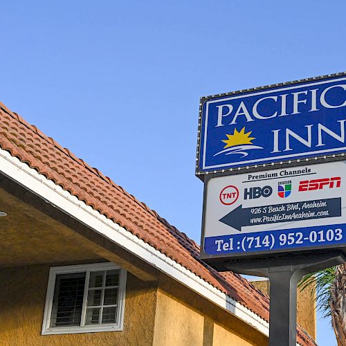 The image shows the sign of Pacific Inn, advertising premium channels like HBO and ESPN. It also includes a phone number: (714) 952-0103.
